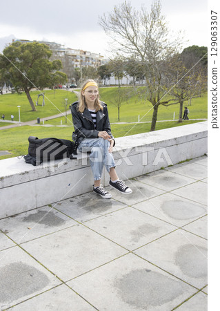 Young woman relaxing in urban park after school or university Young woman relaxing in urban park after school or university 129063307