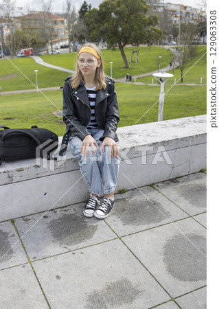 Young student relaxing in urban park after school, enjoying fresh air and green space Young student relaxing in urban park after school, enjoying fresh air and green space 129063308