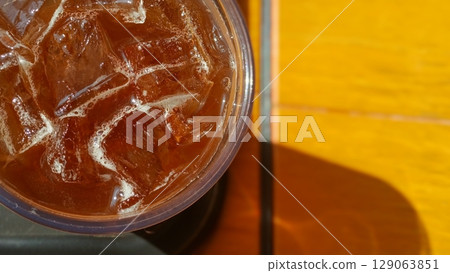 Glass of Iced Coffee on Cafe Table in Bright Sunlight 129063851