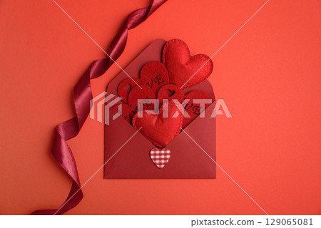 Open red envelope and red felt hearts on red background. Valentines day celebration 129065081