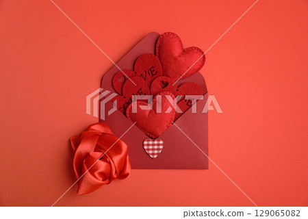 Open red envelope and red felt hearts on red background. Valentines day celebration Open red envelope and red felt hearts on red background. Valentines day celebration 129065082