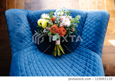 Colorful bridal bouquet resting on a blue velvet armchair Colorful bridal bouquet resting on a blue velvet armchair 129065110
