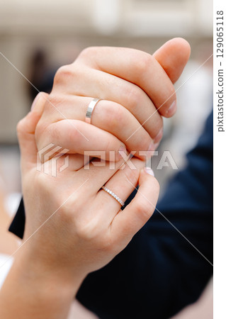 Groom and bride holding hands showing wedding rings 129065118
