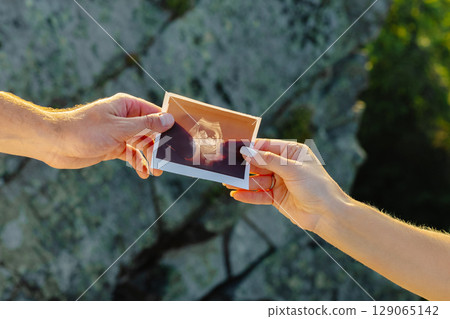 Couple holding ultrasound scan of their baby, pregnancy and parenthood concept 129065142