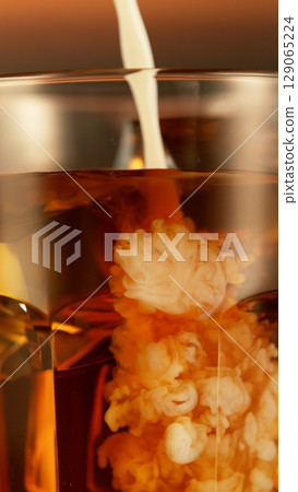 Refreshing coffee with pouring milk into glass, close-up Refreshing coffee with pouring milk into glass, close-up 129065224