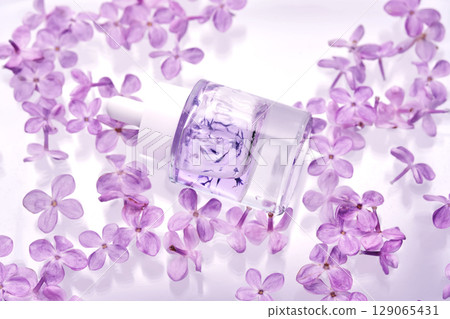 A bottle of hyaluronic serum in lilac flowers in the water. A bottle of hyaluronic serum in lilac flowers in the water. 129065431