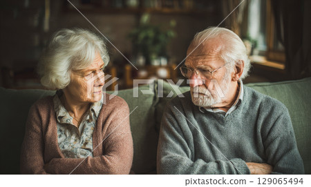 Elderly couple sitting silently on the couch after a quarrel, emotional distance, man and woman offended by each other 129065494