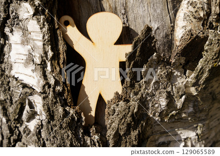 Wooden figure reaching out for help in a natural setting amidst tree bark Wooden figure reaching out for help in a natural setting amidst tree bark 129065589