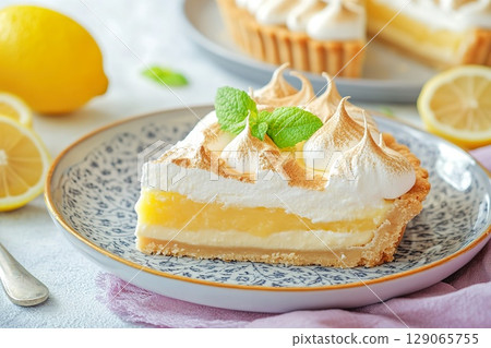 Slice of Lemon Meringue Tart on a Decorative Plate with Lemons. 129065755