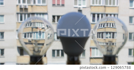 Two old filament bulb and modern LED lamp on a background of facade of an apartment house soft focus concept photo 129065788