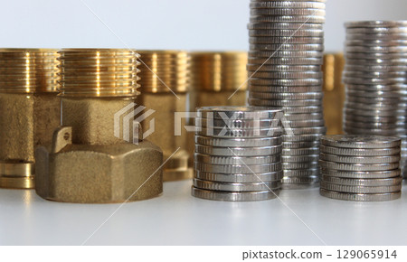 Male Brass Water Meter Fittings And Union Nuts With Columns Of Variety Coins In A Columns Closeup View 129065914