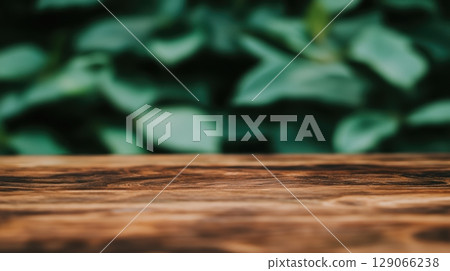 Wooden tabletop with soft green foliage background in a tranquil outdoor setting during daylight 129066238
