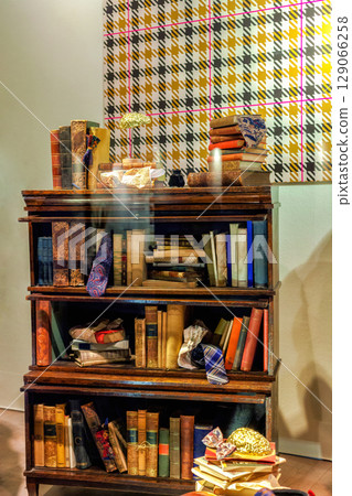 Antique low wooden bookcase filled with row old books, sophisticated and intellectual atmosphere 129066258