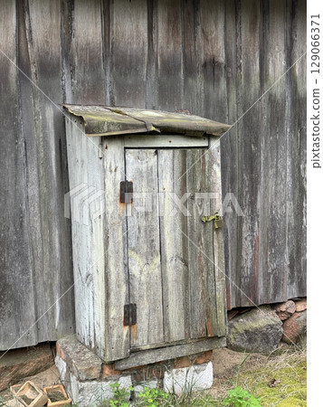 Hasp with padlock on a wooden door. Metal parts rusty and covered with lichen. Hasp with padlock on a wooden door. Metal parts rusty and covered with lichen. 129066371