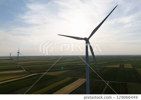 Aerial view of wind turbine on an agricultural filed at sunset. Close up of blades. Aerial view of wind turbine on an agricultural filed at sunset. Close up of blades. 129066449