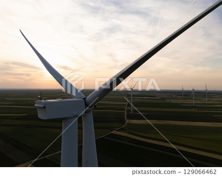 Aerial view of wind turbine on an agricultural filed at sunset. Close up of blades. 129066462
