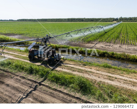 Autonomous machine is moving watering pivot along irrigation canal Autonomous machine is moving watering pivot along irrigation canal 129066472