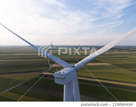 Aerial view of wind turbine on an agricultural filed at sunset. Close up of blades. 129066484