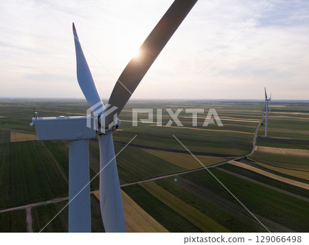 Aerial view of wind turbine on an agricultural filed at sunset. Close up of blades. Aerial view of wind turbine on an agricultural filed at sunset. Close up of blades. 129066498