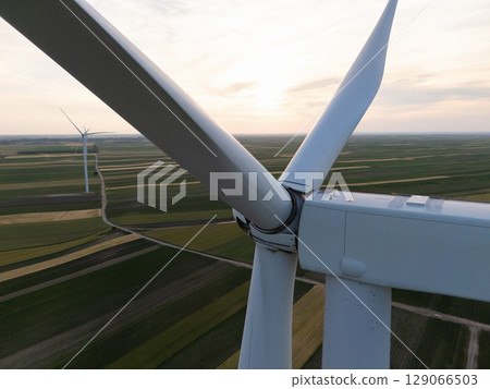 Aerial view of wind turbine on an agricultural filed at sunset. Close up of blades. 129066503