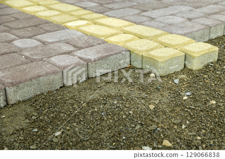 Installation of stone paving slabs in a yard. Installation of stone paving slabs in a yard. 129066838