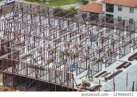 Industrial construction site with workers assembling metal frame building. Development of residential housing in America. Real estate market in the USA 129066851