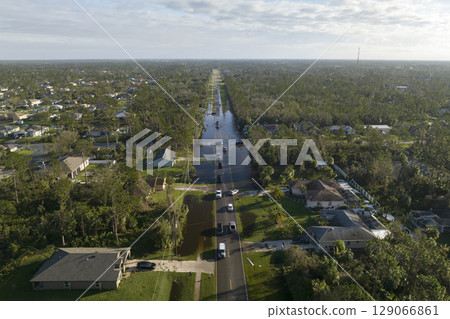 Hurricahe fainfall flooded Florida road with evacuating cars and surrounded with water houses in suburban residential area Hurricahe fainfall flooded Florida road with evacuating cars and surrounded with water houses in suburban residential area 129066861