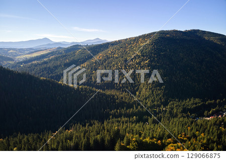 High hills with dark pine woods on autumn bright day. Amazing scenery of wild mountain woodland High hills with dark pine woods on autumn bright day. Amazing scenery of wild mountain woodland 129066875
