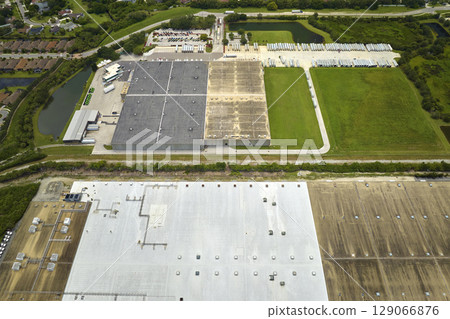 High angle view of big commercial shipping center with many freight trucks unloading and uploading goods for further distribution. Global economy concept High angle view of big commercial shipping center with many freight trucks unloading and uploading goods for further distribution. Global economy concept 129066876