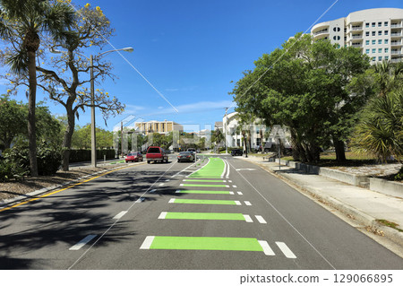 Green bike lane runs on city road side with traffic in Sarasota, Florida, promoting safe cycling and eco-friendly transport on urban street 129066895