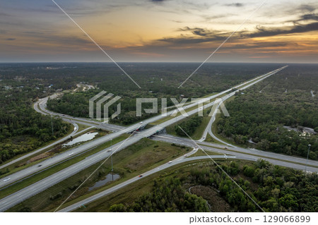 Freeway overpass junction in Florida with fast moving traffic cars and trucks in American rural area at sunset. Interstate transportation infrastructure in USA 129066899