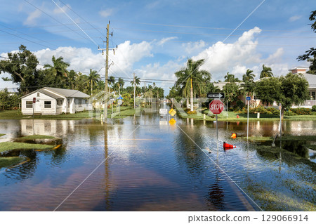 Flooded street in Florida after hurricane rainfall with road closed signs blocking driving of cars. Safety of transportation during natural disaster concept Flooded street in Florida after hurricane rainfall with road closed signs blocking driving of cars. Safety of transportation during natural disaster concept 129066914
