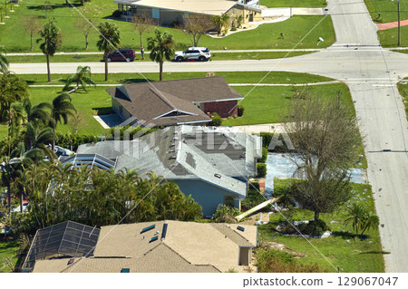 Damaged house roof with missing shingles after hurricane Ian in Florida. Consequences of natural disaster 129067047