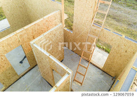 Construction of new and modern modular house. Walls made from composite wooden sip panels with styrofoam insulation inside. Building new frame of energy efficient home concept. Construction of new and modern modular house. Walls made from composite wooden sip panels with styrofoam insulation inside. Building new frame of energy efficient home concept. 129067059