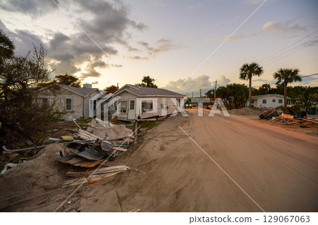Consequences of natural disaster. Trash from severely damaged houses after hurricane storm surge. Piles of debris on street side in Florida 129067063