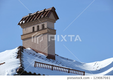 Closeup of house roof top covered with snow in cold winter. Tiled covering of building in wintertime weather 129067081
