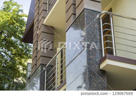 Close up view of part of a building facade with the surface of granite wall. Natural stone materials. Close up view of part of a building facade with the surface of granite wall. Natural stone materials. 129067089