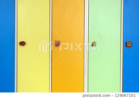 Close up of bright colorful lockers doors with funny animals as door knobs in day care school 129067101