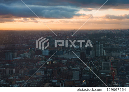 The London Eye stands prominently against a sunset sky, with clouds adding depth. The cityscape features diverse architecture, capturing London's urban landscape. The London Eye stands prominently against a sunset sky, with clouds adding depth. The cityscape features diverse architecture, capturing London's urban landscape. 129067264