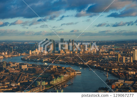 Aerial view of London's Canary Wharf skyline with modern skyscrapers. The River Thames reflects the warm glow of the setting sun during Christmas. Aerial view of London's Canary Wharf skyline with modern skyscrapers. The River Thames reflects the warm glow of the setting sun during Christmas. 129067277