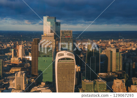 The iconic London skyline features the Walkie Talkie and Leadenhall buildings, bathed in golden light against a dark, cloudy sky during the Christmas period. The iconic London skyline features the Walkie Talkie and Leadenhall buildings, bathed in golden light against a dark, cloudy sky during the Christmas period. 129067293