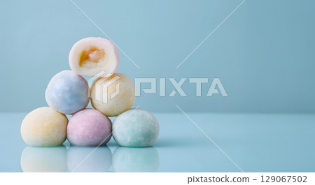 Soft rice cake pieces in pastel colors stacked on reflective surface, evoking sense of sweetness and delight 129067502