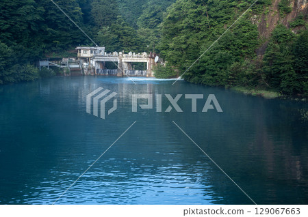 Shirasada Dam surrounded by deep greenery and the emerald green lake surface Shirasada Dam surrounded by deep greenery and the emerald green lake surface 129067663
