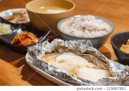 A home-style Japanese dinner set featuring foil-wrapped food, multigrain rice, and miso soup 129067861