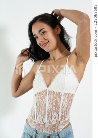 Young latin woman touching her hair and smiling on white background Young latin woman touching her hair and smiling on white background 129068695