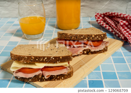 Healthy ham, cheese, and tomato sandwiches served on board with natural beverage 129068709