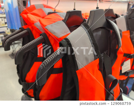 Brightly colored life vests hang in a retail store ready for summer adventures 129068759