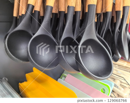 Kitchen utensils hang elegantly showcasing black ladles and vibrant tools 129068766