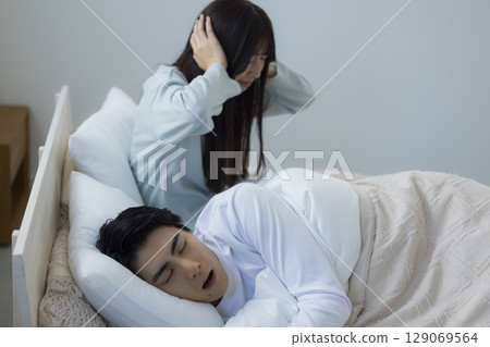 A young man sleeping and snoring in bed 129069564