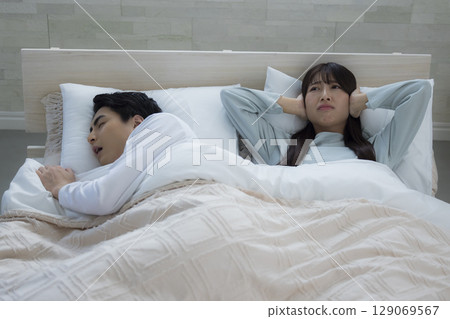 A young man sleeping and snoring in bed 129069567
